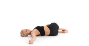 a woman doing the yoga pose supine twist on her back to relieve back pain and feel better
