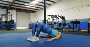 woman doing a glute bridge from a beginners workout for lower back pain. displayed to show the importance of strengthening the glutes to relieve back pain and feel better