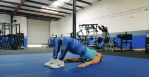 woman doing a glute bridge from a beginners workout for lower back pain. displayed to show the importance of strengthening the glutes to relieve back pain and feel better